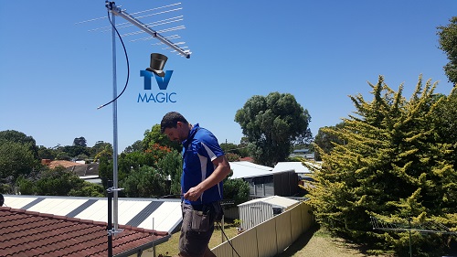 Technician installing an aerial. TV Magic logo beneath top of aerial