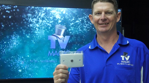 Technician - Brendan, holding up a TV point. Standing in front of a large TV screen with TV Magic logo on screen