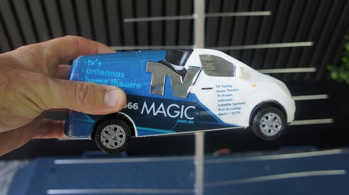 Technician holding a mini TV Magic van up in front of an antenna