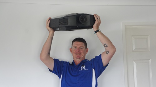 Technician - Brendan, holding up a projector ready for installation