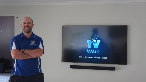 Technician in front of a TV and soundbar he installed