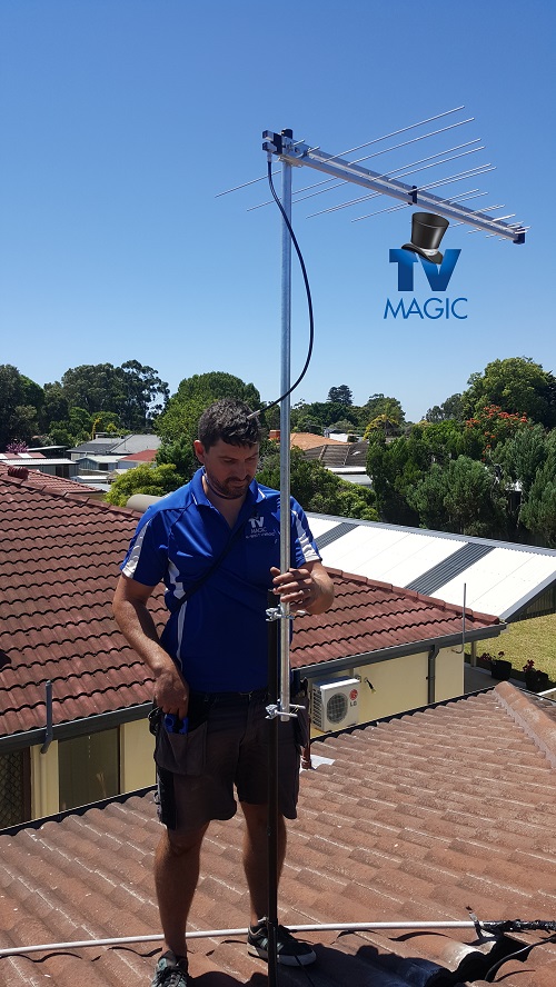 Technician standing on a roof with an antenna. TV Magic logo included