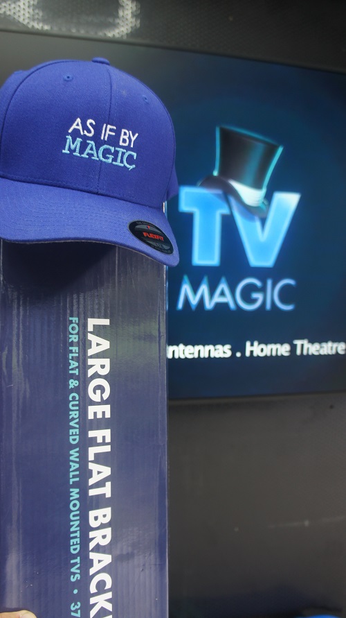 Wall mounted TV with TV Magic wall bracket in front of it. TV Magic cap on top