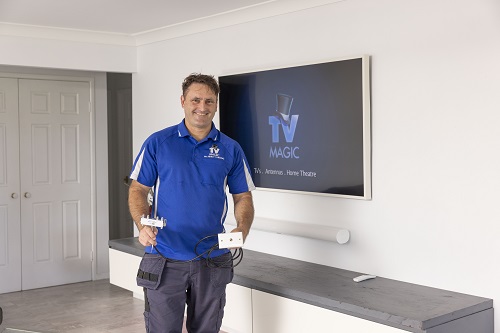 Technician holding a TV point next to a wall mounted TV and soundbar