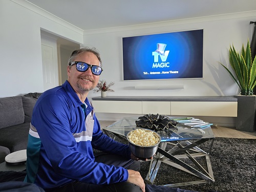 Technician wearing TV Magic sunglasses in front of a large screen. Popcorn in hand