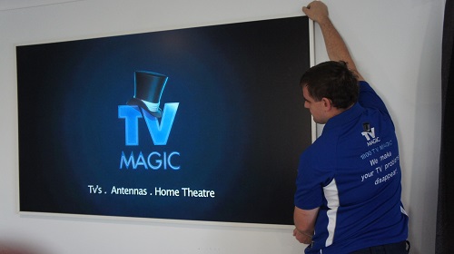 Technician installing a large TV.