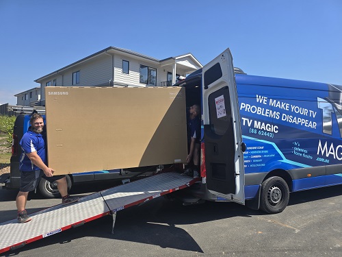 Technicians loading a large TV