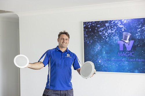 Technician holding speakers up in front of a large screen