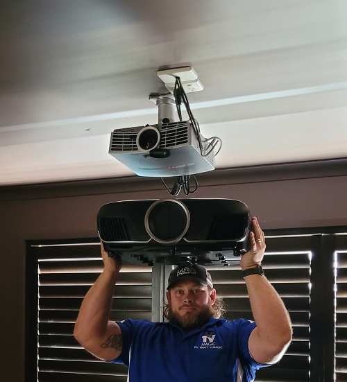 Technician holding up a projector, ready to replace the old one