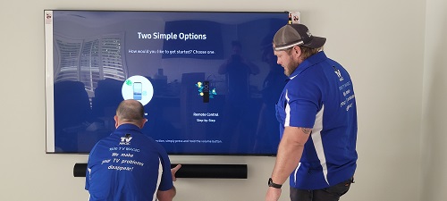 Technicians mounting a soundbar and TV for a customer.