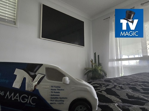 Wall mounted TV - mini TV Magic van on floor beneath it.
