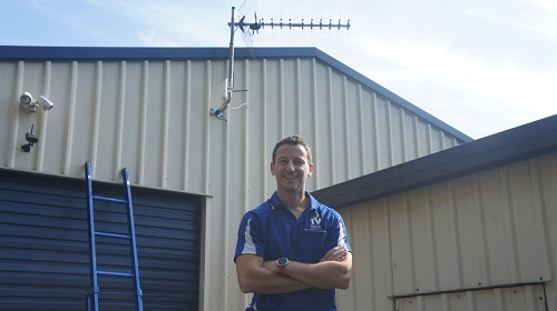 Technician standing below an antenna installation he completed in Stake Hill