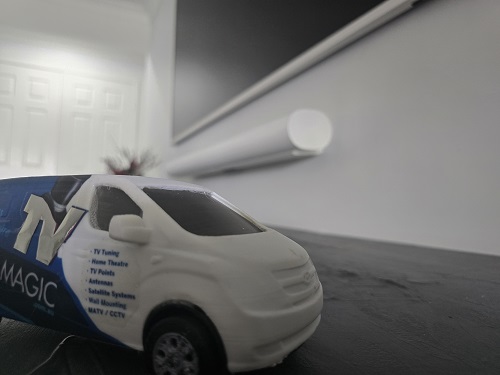 Close up of a wall mounted TV and soundbar. Mini TV Magic van below