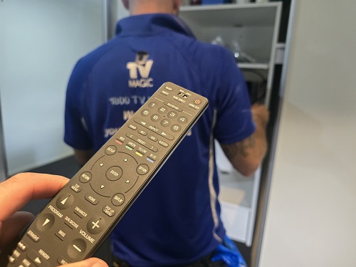 A TV remote held up behind technicians back