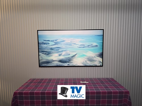 A wall mounted TV. Logo bottom centre