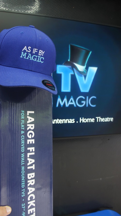 Wall mounted TV with TV Magic wall bracket in front. TV Magic cap on top of bracket