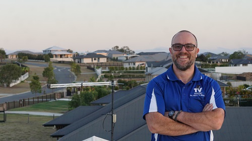 Technician on a roof next to an aerial installation.