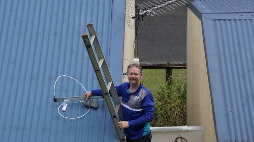 Technician on a ladder finishing up an antenna installation