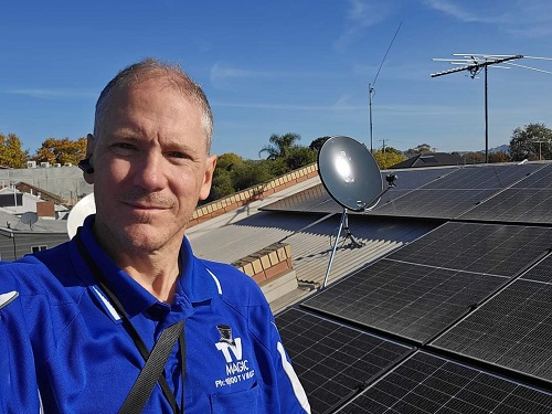 Technician - Robert, with a satellite dish he installed for Christian TV