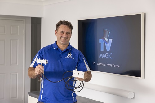 Technician holding a TV point, standing in front of a wall mounted TV.