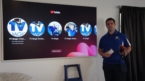Technician holding a TV point, standing in front of a large TV