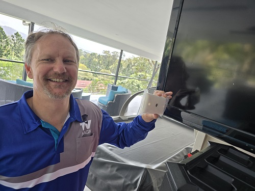 Technician holding up a TV point in front of a TV