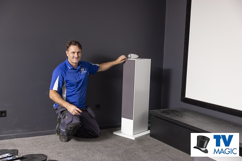 Technician in a home cinema he built. Logo in bottom right corner