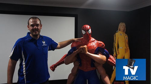 Technician with life size movie characters in a home cinema he designed.