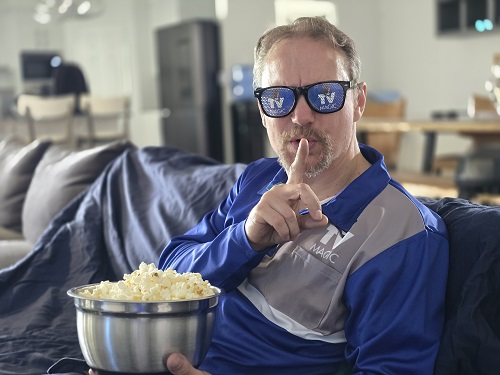 Technician going "sssshhhhh", holding a bowl of popcorn, wearing TV Magic sunglasses.