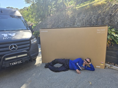 Technician with a massive TV box from a delivery