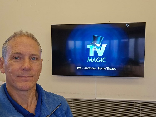 technician - Robert, in front of a new TV installation.
