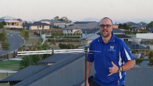 Technician next to an antenna installation - giving the thumbs up.