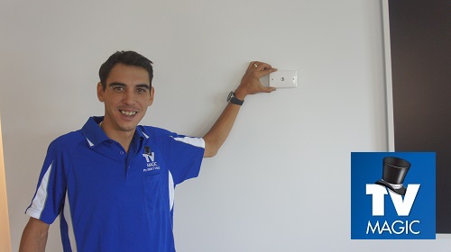 Technician holding a TV Point up to a wall. TV Magic logo in bottom right corner