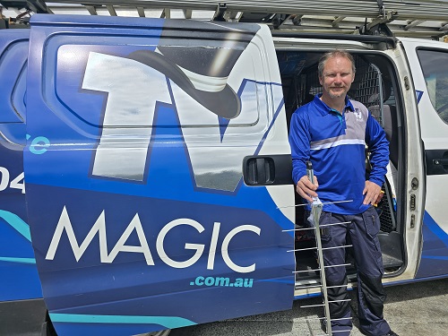 Technician holding an antenna next to his van