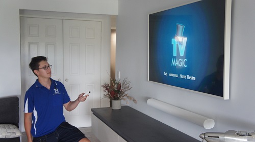 Technician holding a remote in front of large wall mounted TV