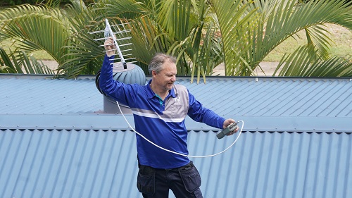Technician holding an antenna, testing signal strength