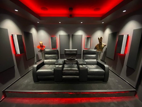A home theatre setup with black leather seating and red strip lighting