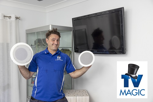 Technician with speakers in hand, ready for a multi-room audio installation.