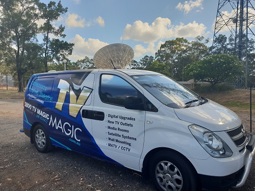Technician van, in front of large satellite dish install