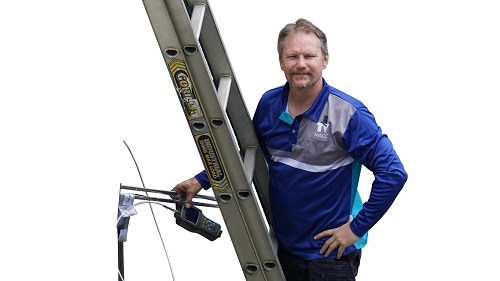 Technician on a ladder with a signal meter and antenna