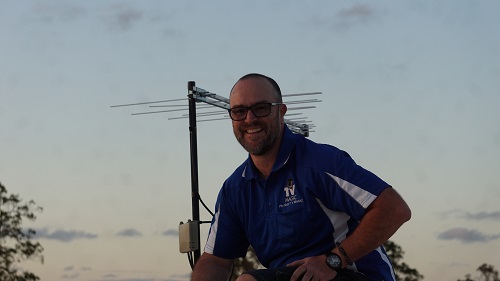 Technician sitting on a roof in front of an antenna installation