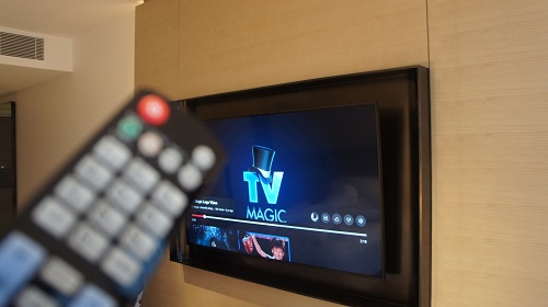 Wall mounted TV with remote in front of it.