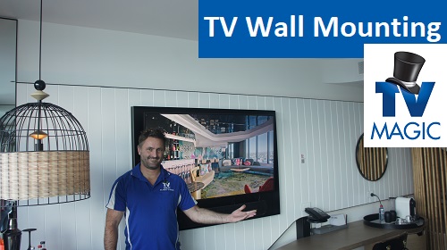 Technician with a wall mounted TV. Caption "TV Wall Mounting" With Logo