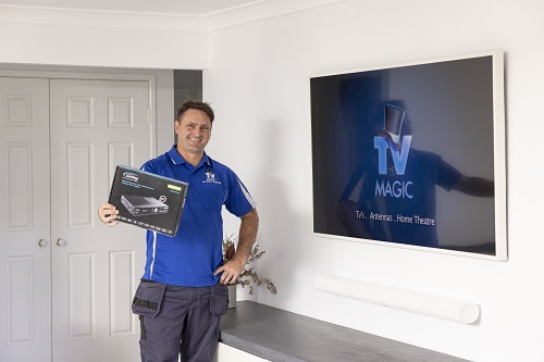 Technician holding a Vast box next to a wall mounted TV