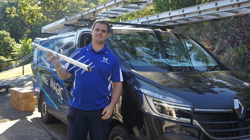 Technician standing next to his van holding an antenna.