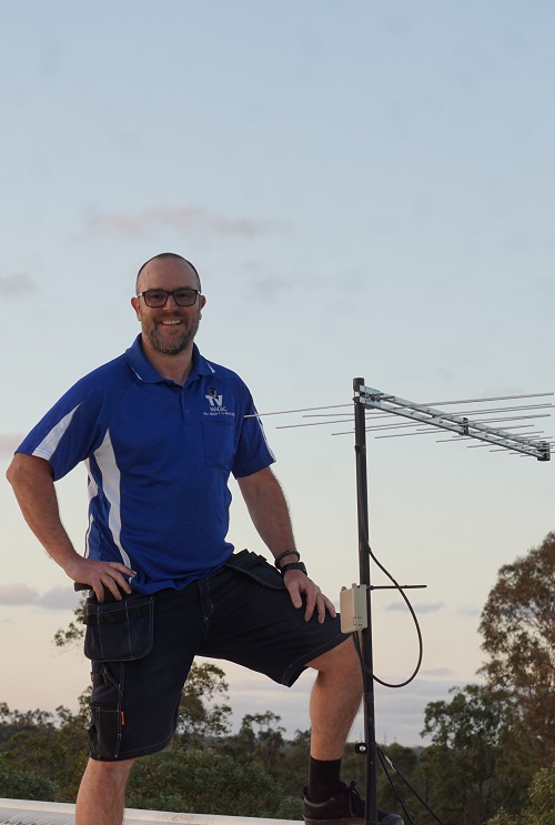 Technician standing next to a new antenna installation
