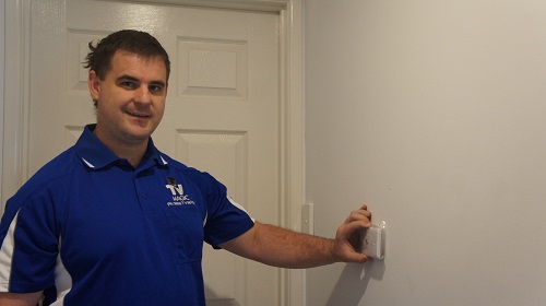 Technician holding a TV point up to a wall