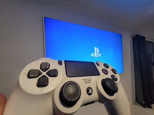 Large screen with PlayStation logo. Gaming remote in front 