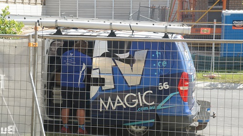 Technician in his van in front of a build, preparing for a pre-wire fit out
