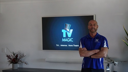 Technician in front of a large TV and soundbar he mounted